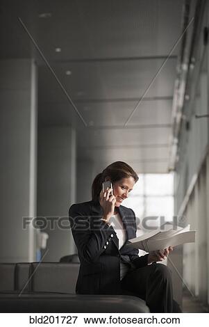 Stock Photo - Caucasian businesswoman holding paperwork and talking on cell phone. Fotosearch