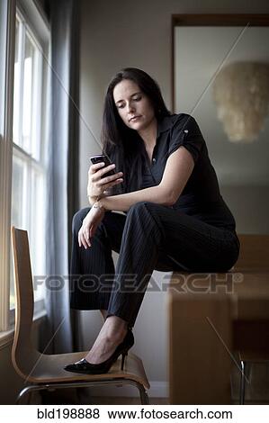 Stock Photo - Caucasian businesswoman sitting in table using cell phone. Fotosearch