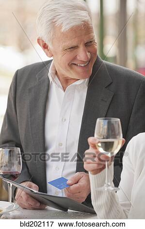 Stock Photo - Caucasian couple drinking wine and paying bill. Fotosearch