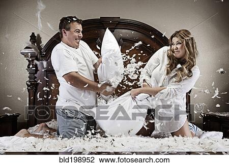 Stock Image - Caucasian couple having pillow fight. Fotosearch