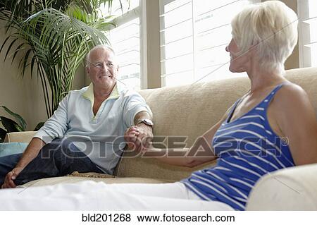 Stock Photo - Caucasian couple holding hands on sofa. Fotosearch
