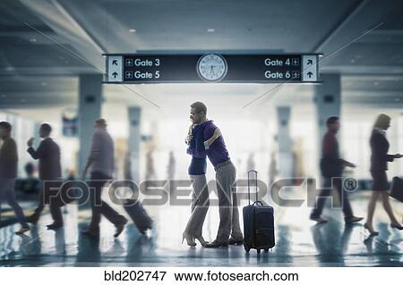 Stock Photo - Caucasian couple hugging in airport. Fotosearch