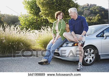 Stock Photo - Caucasian couple leaning on car. Fotosearch