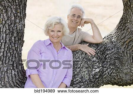 Stock Photo - Caucasian couple leaning on tree. Fotosearch