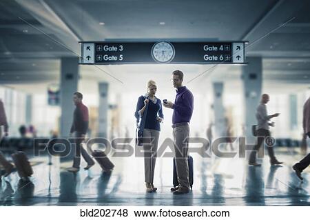 Caucasian couple looking at cell phone in airport View Large Photo Image Stock Photo - Caucasian couple looking at cell phone in airport. Fotosearch