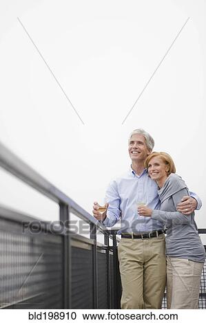 Stock Image - Caucasian couple on balcony drinking wine together. Fotosearch