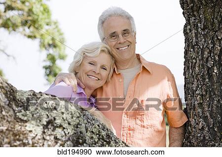 Stock Image - Caucasian couple posing near tree. Fotosearch