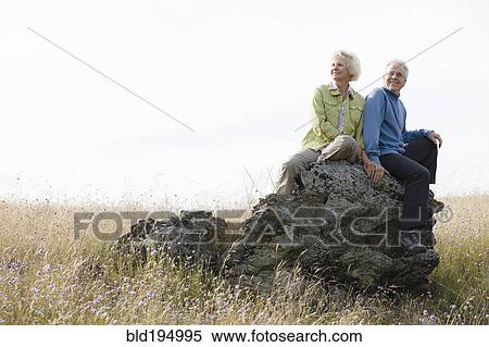 Caucasian couple sitting on rock in field View Large Photo Image Stock Photography - Caucasian couple sitting on rock in field. Fotosearch