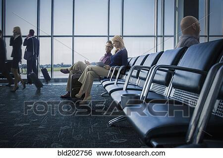 Stock Photograph - Caucasian couple using digital tablet in airport. Fotosearch