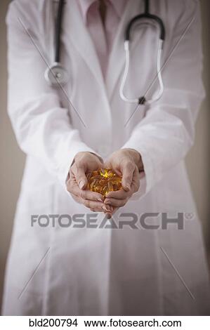 Picture - Caucasian doctor holding pills. Fotosearch