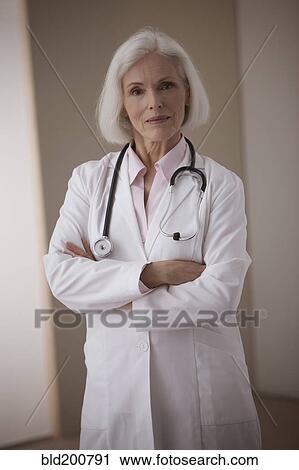 Stock Image - Caucasian doctor standing with arms crossed. Fotosearch