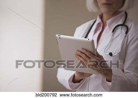 Stock Image - Caucasian doctor using digital tablet. Fotosearch