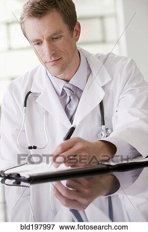 Stock Photo - Caucasian doctor writing in medical record. Fotosearch