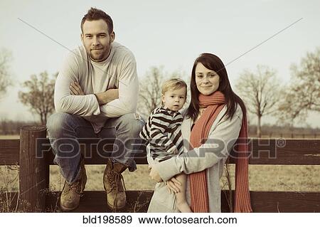Stock Photo - Caucasian family standing near wooden fence. Fotosearch
