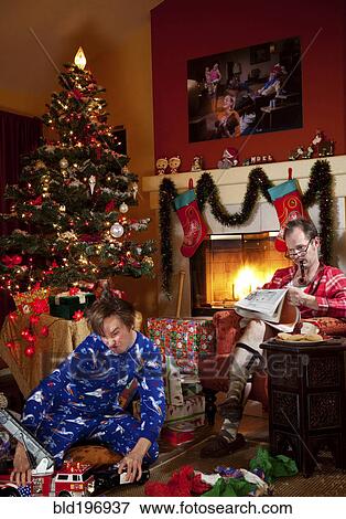 Stock Photo - Caucasian father and son in living room on Christmas morning. Fotosearch
