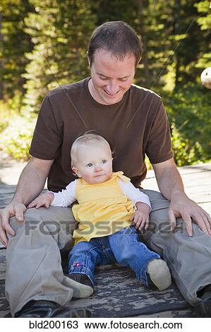 Stock Image - Caucasian father sitting with daughter. Fotosearch