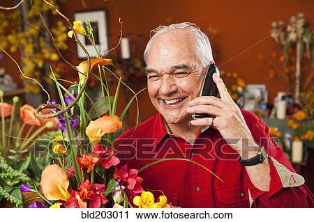 Stock Image - Caucasian florist talking on phone in shop. Fotosearch