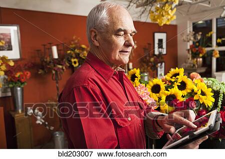 Stock Photo - Caucasian florist using tablet computer in shop. Fotosearch