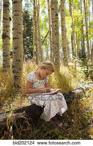 Picture - Caucasian girl using digital tablet in woods. Fotosearch
