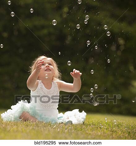 Stock Photography - Caucasian girl watching floating bubbles. Fotosearch