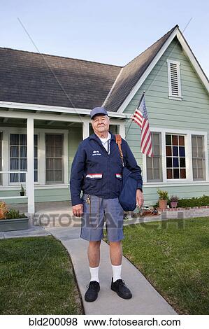Stock Photo - Caucasian mailman standing in front yard. Fotosearch
