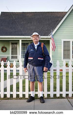 Stock Photo - Caucasian mailman standing on sidewalk. Fotosearch