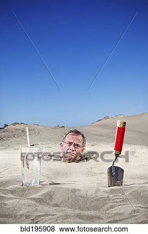 Caucasian man buried in sand next to glass of water and trowel View Large Photo Image Stock Photo - Caucasian man buried in sand next to glass of water and trowel. Fotosearch