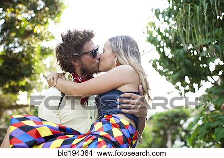 Picture - Caucasian man carrying and kissing girlfriend. Fotosearch