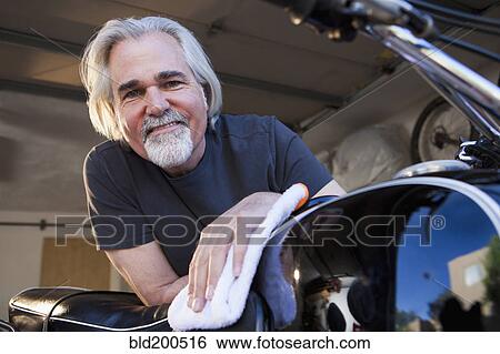 Stock Photograph - Caucasian man cleaning motorcycle. Fotosearch