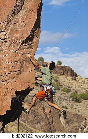 Stock Image - Caucasian man climbing rocks. Fotosearch
