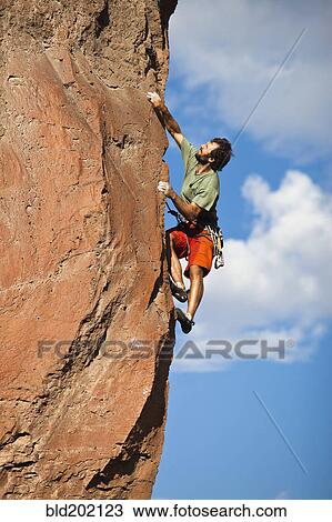 Stock Image - Caucasian man climbing rocks. Fotosearch