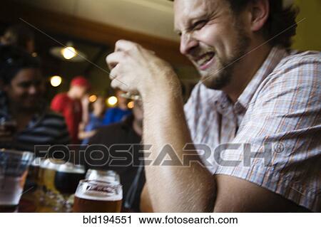 Stock Image - Caucasian man drinking in bar. Fotosearch