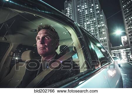 Stock Photograph - Caucasian man driving on city street. Fotosearch