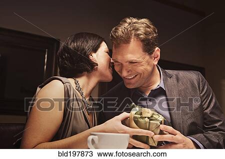 Stock Image - Caucasian man giving woman gift in restaurant. Fotosearch