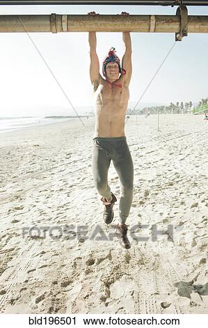 Stock Image - Caucasian man hanging from pipe. Fotosearch