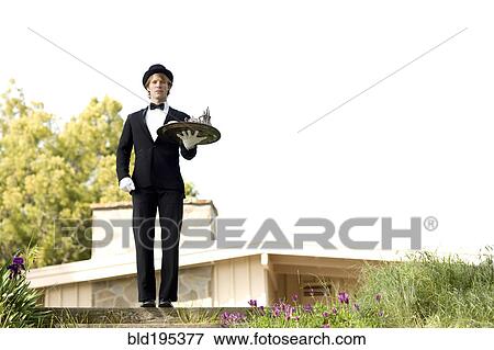 Stock Photo - Caucasian man in tuxedo carrying tray. Fotosearch