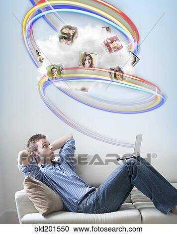 Stock Image - Caucasian man looking at colorful lines and images above his head. Fotosearch