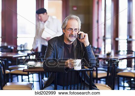 Caucasian man on cell phone in restaurant View Large Photo Image Stock Photo - Caucasian man on cell phone in restaurant. Fotosearch