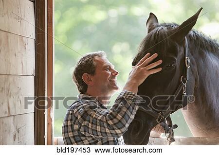 Stock Image - Caucasian man petting horse. Fotosearch