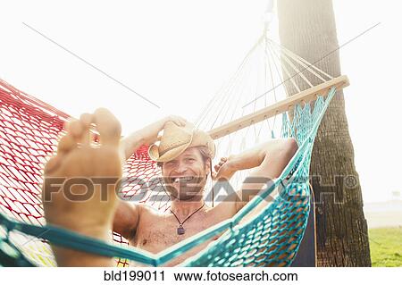 Stock Image - Caucasian man relaxing in hammock. Fotosearch