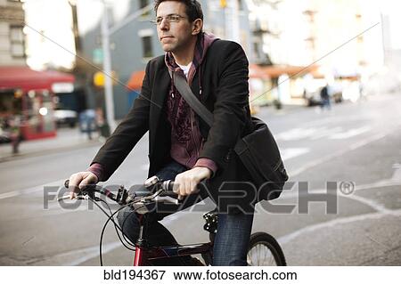 Caucasian man riding bicycle on urban street View Large Photo Image Stock Photo - Caucasian man riding bicycle on urban street. Fotosearch