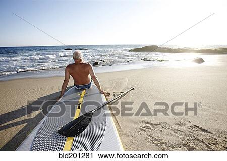 Caucasian man sitting on paddleboard View Large Photo Image Stock Image - Caucasian man sitting on paddleboard. Fotosearch