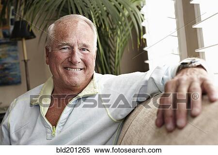 Stock Photography - Caucasian man sitting on sofa. Fotosearch