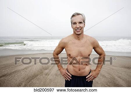 Stock Photo - Caucasian man standing on beach. Fotosearch
