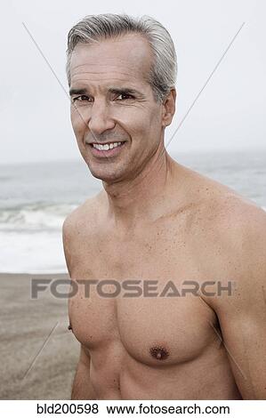 Stock Photo - Caucasian man standing on beach. Fotosearch