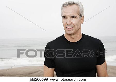 Stock Photo - Caucasian man standing on beach. Fotosearch