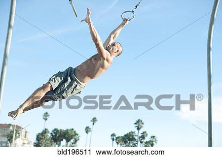 Caucasian man swinging on gymnastic rings View Large Photo Image Stock Image - Caucasian man swinging on gymnastic rings. Fotosearch