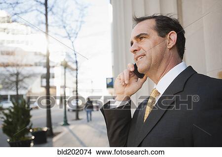 Picture - Caucasian man talking on cell phone outdoors. Fotosearch