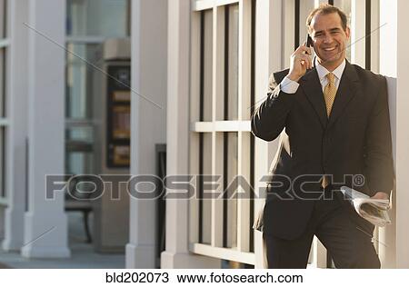 Stock Image - Caucasian man talking on cell phone outdoors. Fotosearch