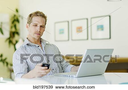 Stock Photo - Caucasian man text messaging on cell phone. Fotosearch